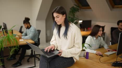 Focused-brunette-woman-sitting-on-the-table-with-laptop,-trying-to-solve-the-problem