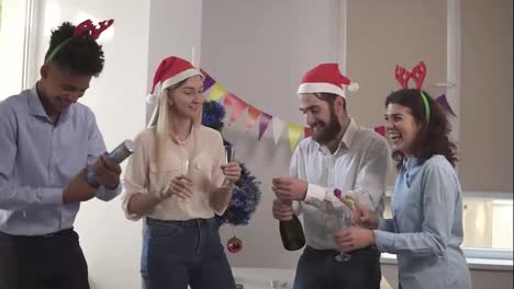 Gruppe-Junger-Leute,-Die-Weihnachten-Und-Neujahr-Im-Büro-Feiern-Und-Eine-Flasche-Sekt-Und-Squib-Petarden-Mit-öffnen