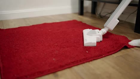A-person-vacuums-the-floor-and-removes-dust-and-dirt-from-the-red-carpet