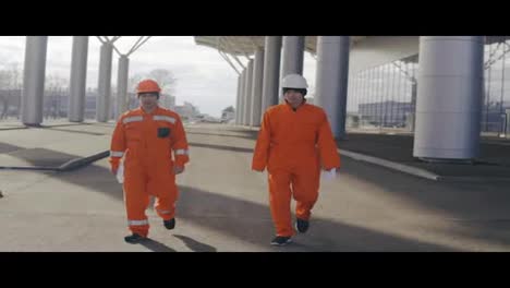 Two-happy-construction-workers-walking-and-jumping-together