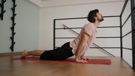 yoga-master-workout-on-red-mat-in-modern-apartment,-slow-motion