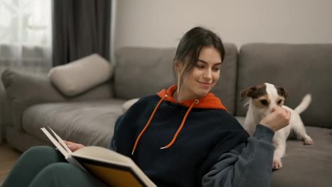 A-beautiful-woman-reading-book-and-caress-her-pet-dog-on-the-couch-at-home