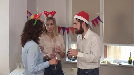 Young-office-workers-talking-and-holding-glasses-with-sparkling-wine-during-christmas-party-in-the-office-while-their-african