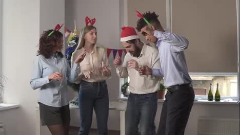 Slow-Motion-shot:-Group-of-happy-office-workers-dancing-during-corporate-New-Year-party-wearing-christmas-hats-and-deer-headband