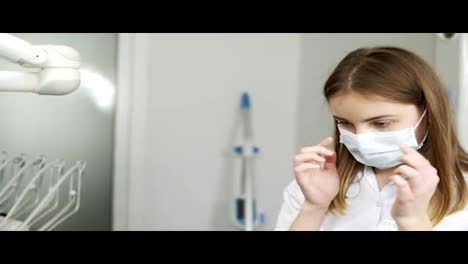 Close-up-of-young-female-dentist-wearing-protective-glasses-at-the-dentist-cabinet.-Brown-Haired-woman-in-medical-mask-and