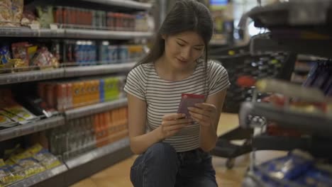 and-Asian-girl-visitor-chooses-one-of-two-products.-Happy-shot-visitor.-Choice-of-products-in-the-store