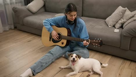 Junges-Mädchen-Spielt-Gitarre-Und-Sitzt-Mit-Ihrem-Schönen-Hund-Auf-Dem-Boden