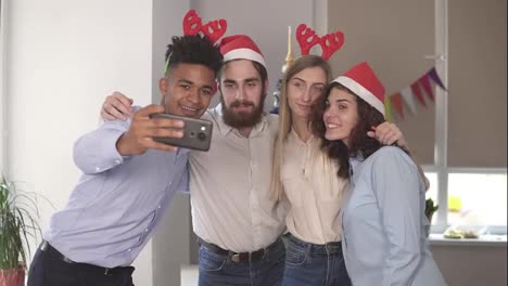 Gente-De-Negocios-Feliz-Con-Sombreros-De-Santa-Se-Hace-Selfie-Y-Sonríe-Mientras-Celebra-El-Año-Nuevo-En-La-Oficina