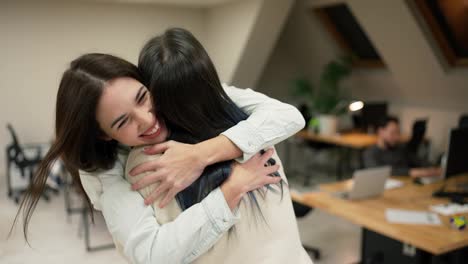 Young-female-office-workers-hugging-to-congratulate-a-colleague-or-missing-a-friend-from-vacation,-slow-motion