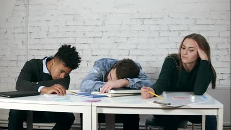 Junge-Studierende-Langweilen-Sich-Während-Der-Vorlesungszeit,-Während-Einer-Von-Ihnen-Am-Tisch-Sitzend-Schläft