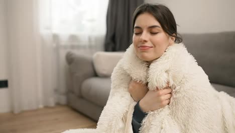 Portrait-of-young-beautiful-woman-in-warm-fur-blanket-at-home