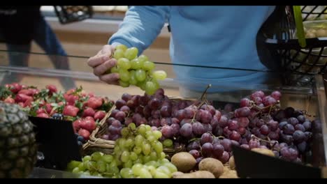 Male-hand-choosing-grapes-in-the-supermarket,-putting-to-the-basket