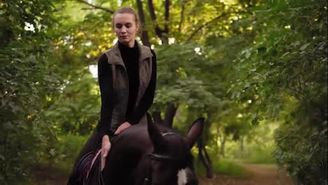 Attractive-woman-riding-beautiful-brown-horse-in-park-during-sunny-day-and-stroking-the-horse's-head.-Beautiful-female-rider