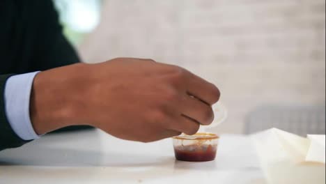 Young-african-american-dips-chicken-nugget-in-sauce-and-eats-it-looking-in-the-camera-during-lunch-at-work-in-Slow-Motion