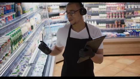 Mixed-race-seller-man-use-tablet-in-supermarket-feeling-happy-dancing,-listening-music