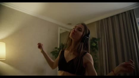 Slow-motion-of-happy-young-lady-in-headphones-dancing-and-moving-in-bra