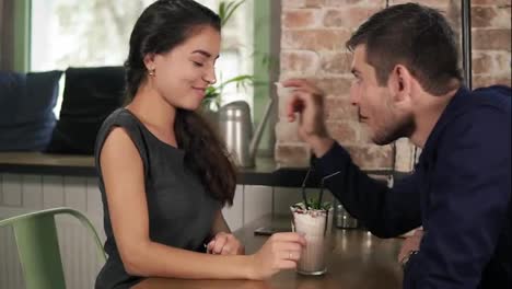 Attractive-couple-playing-and-being-silly-with-milk-shake-in-cafe-putting-whipped-cream-on-each-others-nose