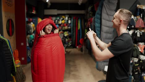 A-smiling-couple-purchase-in-sportswear-store-taking-pictures-inside-the-sleeping-bag