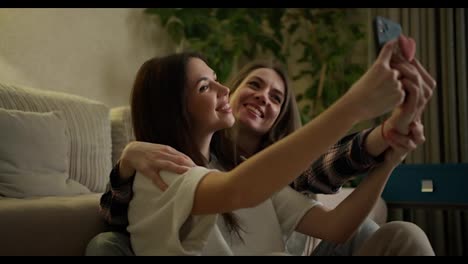 Dos-Mujeres-Haciendo-Selfie-Por-Teléfono-Inteligente-Sentadas-En-El-Suelo-En-Casa