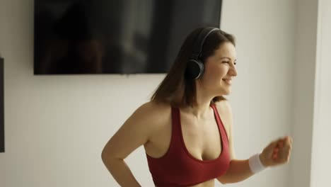 Happy-brunette-woman-in-headphones-dancing-at-home