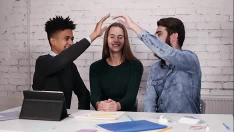 Multi-ethnic-business-team-giving-high-five-sitting-at-the-table-in-modern-office.-Slow-Motion-shot