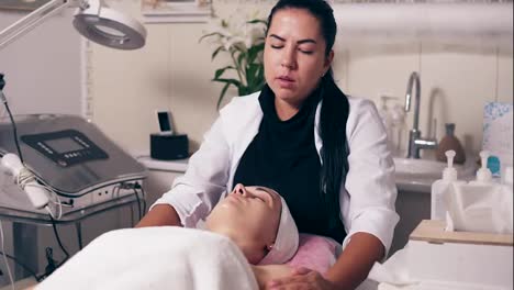 Female-cosmetologist-is-making-neck-massage-in-spa-salon.-Young-woman-with-her-eyes-closed-is-lying-on-the-couch-during-cosmetic