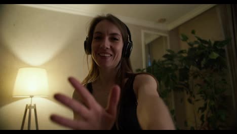 Slow-motion-of-happy-young-lady-in-headphones-dancing-and-moving,-looking-to-the-camera