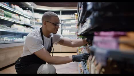 Handsome-worker-in-glasses-rearranging-goods-on-the-shelves