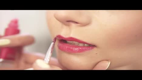 Make-up-artist-applying-rose-lipstick-using-a-brush.-Close-Up-view.-Slow-Motion-shot