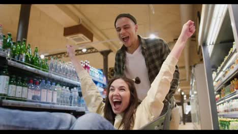 Close-up-of-a-young-couple-having-fun,-man-pushing-shopping-cart-with-his-girlfriend-inside