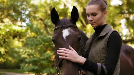 Close-Up-view-of-young-beautiful-woman-petting-brown-horse-while-standing-in-the-green-field