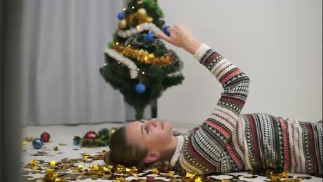 Feliz-Chica-Festiva-Tirada-En-El-Suelo-Con-Confeti-Dorado-Brillante-Y-Tomándose-Selfie.-árbol-De-Navidad-Decorado-En-El-Fondo