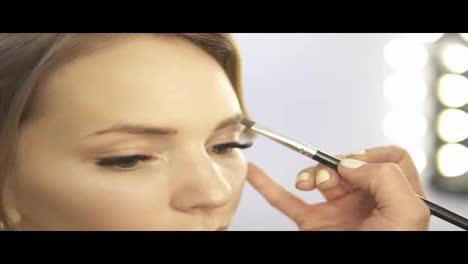 Close-Up-view-of-makeup-artist-applying-eyeshadow-on-eyelid-using-makeup-brush.-Professional-makeup.-Slow-Motion-shot