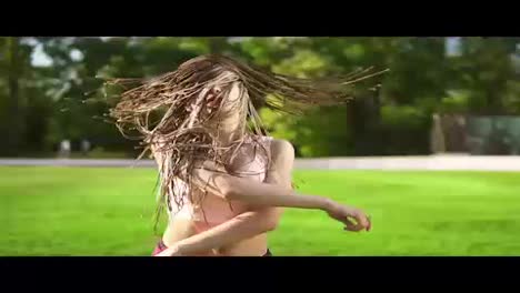Young-beautiful-girl-with-dreads-dancing-in-a-park.-Beautiful-woman-listening-to-music-and-dancing-during-a-sunny-day