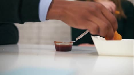 Close-Up-view-of-young-african-american-hand-dips-chicken-nugget-in-sauce-during-lunch-at-work-in-Slow-Motion