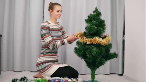 Attraktive-Glückliche-Frau,-Die-Am-Künstlichen-Weihnachtsbaum-Sitzt-Und-Ihn-Zu-Hause-Schmückt