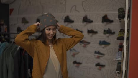 Portrait-of-a-adult-woman-trying-on-a-new-colorful-winter-hat-in-a-store