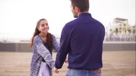 Close-Up-view-of-a-young-couple-on-the-beach-holding-hands-and-walking-together,-looking-in-the-eyes-and-smiling-happily