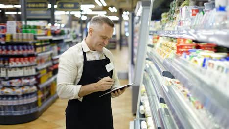 A-middle-aged-worker-checks-the-goods-on-the-shelves-in-the-dairy-department.-Inventory.-Goods-control
