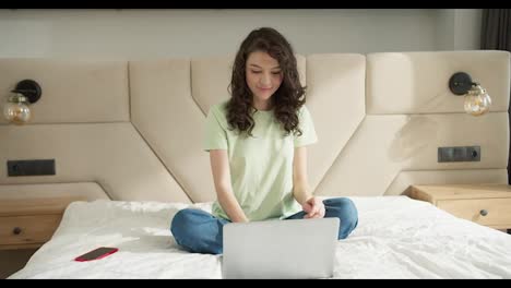 Woman-celebrating-success-on-laptop-while-sitting-on-the-bed