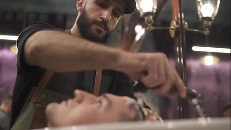 Image-of-stylish-male-barber-washing-hair-of-his-client-for-making-modern-haircut-in-barber-shot