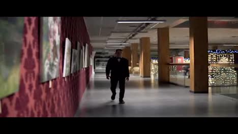 Young-blonde-man-in-a-black-suit-with-bow-tie-walking-in-the-art-gallery.-Slow-Motion