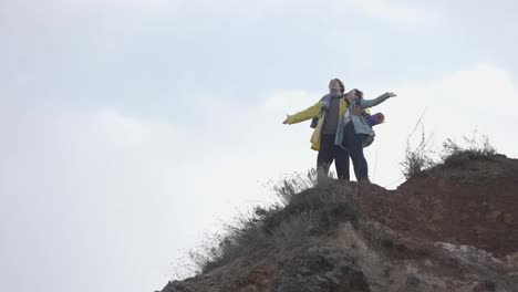 Two-hikers-standing-on-top-of-a-mountain-with-outstretched-hands-and-enjoying-the-view