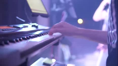 Close-Up-man-pianist-hands-play-electric-piano-in-night-bar-under-flashes-of-colourful-lights.-Slow-Motion-shot