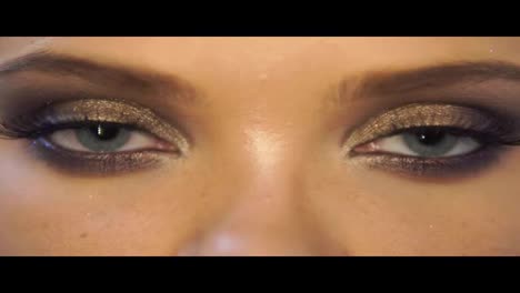 Close-Up-view-of-woman's-eyes-with-beautiful-golden-makeup-opening-and-closing-in-Slow-Motion