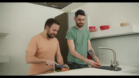 Couple-gay-help-to-prepare-food-that-one-wash-vegetable-and-the-other-slice-vegetable-at-kitchen