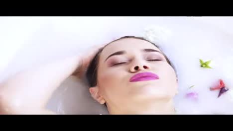 Close-Up-view-of-young-woman's-head-bathing-in-milk-bath-filled-with-flowers.-Spa-and-skin-care-concept.-Slow-Motion-shot