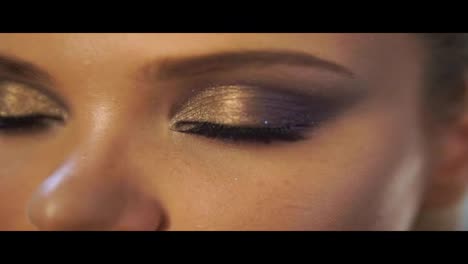 Close-Up-view-of-woman's-eyes-with-beautiful-golden-makeup-opening-in-Slow-Motion