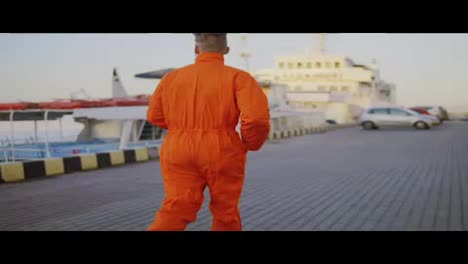 Worker-in-orange-uniform-is-running-in-the-harbour.-Slow-Motion-shot