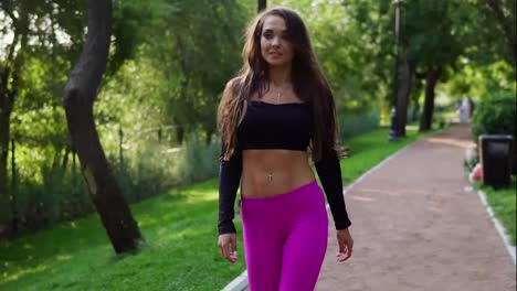 Beautiful-brunette-woman-in-short-sport-top-walking-in-the-park-after-intensive-training.-Fit-healthy-sport-woman-exercising-in